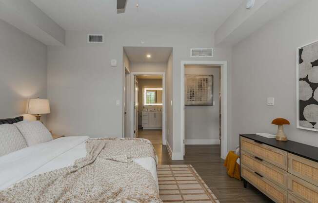 A bedroom with a bed, dresser, and a painting on the wall.