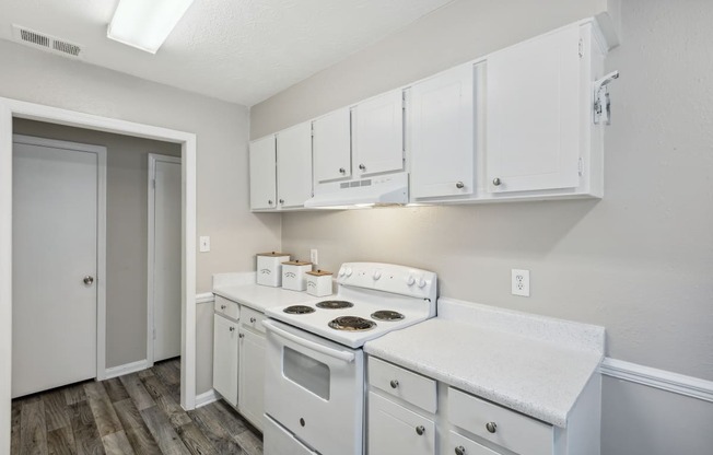 a white kitchen with white cabinets and a white stove top oven