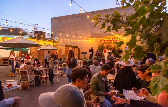 A group of people are sitting at tables outside a restaurant.