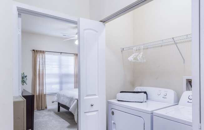 a laundry room with a washer and dryer and a bedroom with a bed