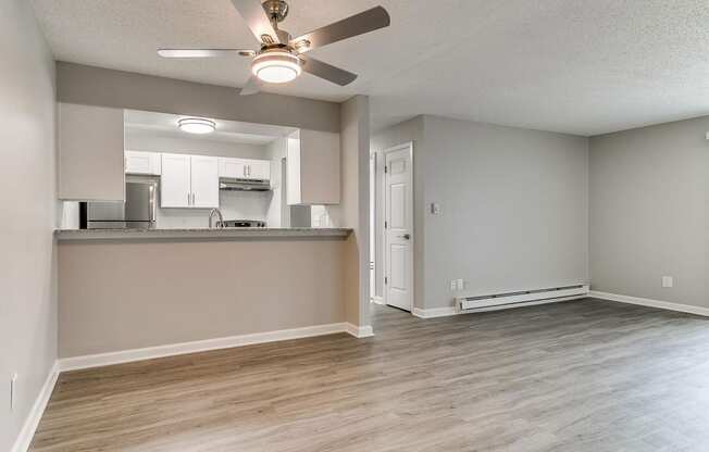 an empty living room and kitchen with a ceiling fan