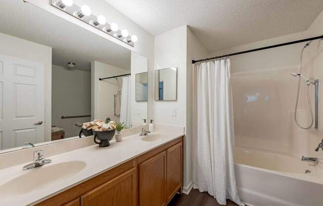 A bathroom with a white tub, sink, and shower curtain.