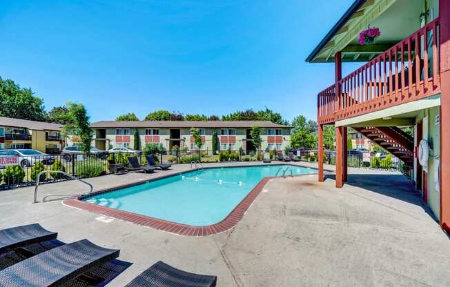 a swimming pool with lounge chairs and a building in the background