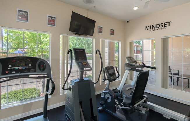 a gym with exercise machines and a tv