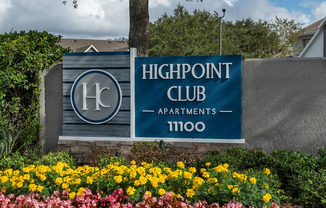 a sign for the highpoint club apartments in front of flowers