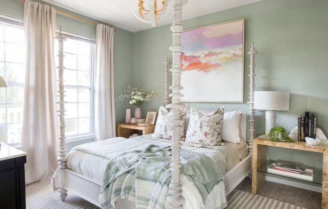 a bedroom with a white four poster bed and a large painting on the wall