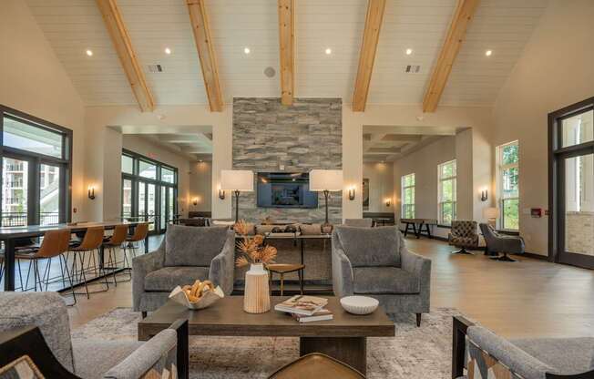 A living room with a stone fireplace and wooden beams at The Ashton at East Park Apartments, Kennesaw