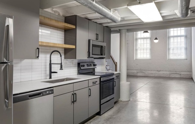 a kitchen with white counter tops and stainless steel appliances at Highland Mill Lofts, Charlotte, 28205