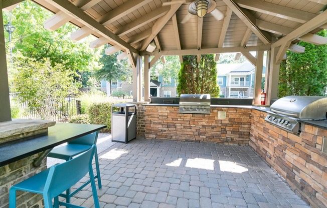 a covered outdoor kitchen with a brick wall and a grill