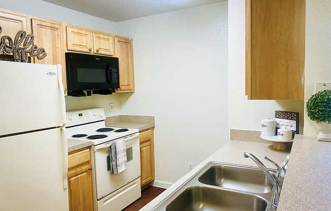 A kitchen with a white refrigerator, a black microwave, and a white oven.