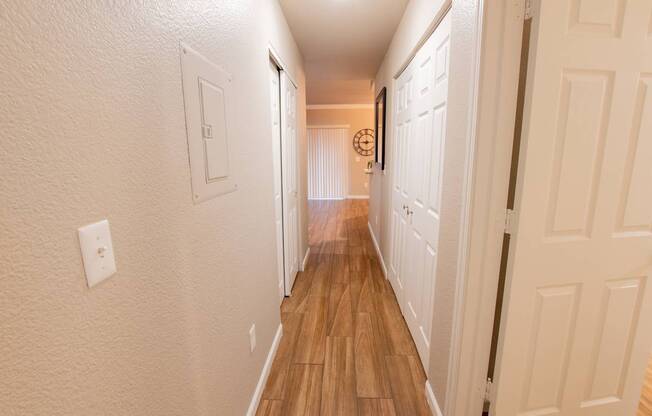 a long hallway with wood floors and white closets and doors