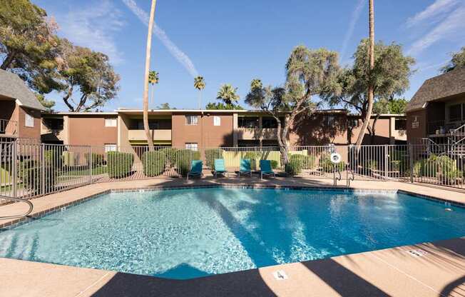 a swimming pool with chairs in front of a building