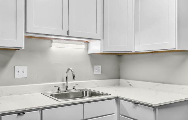 A kitchen with white cabinets and a sink.