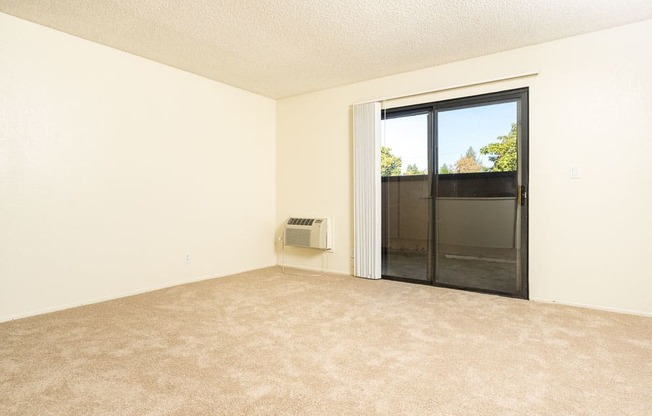 an empty living room with a sliding glass door to a patio