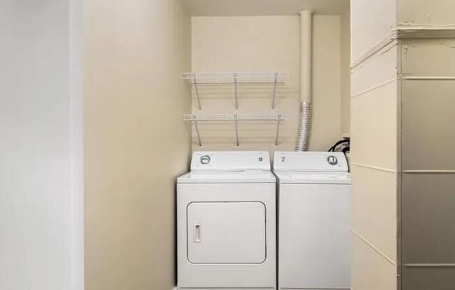Two white front loading washing machines in a laundry room.