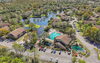 A bird's eye view of a residential area with a swimming pool and a lake.