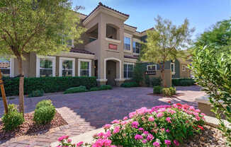 A house with a driveway and pink flowers in front.