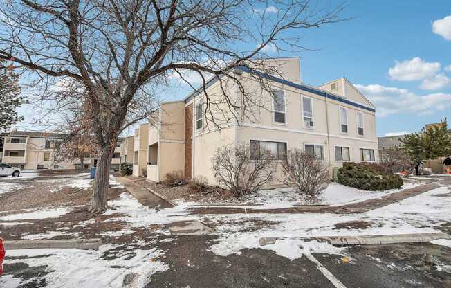 A large beige building with a tree in front of it.