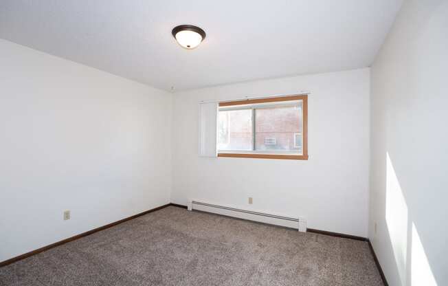 an empty room with carpet and a window. Fargo, ND Country Club Apartments