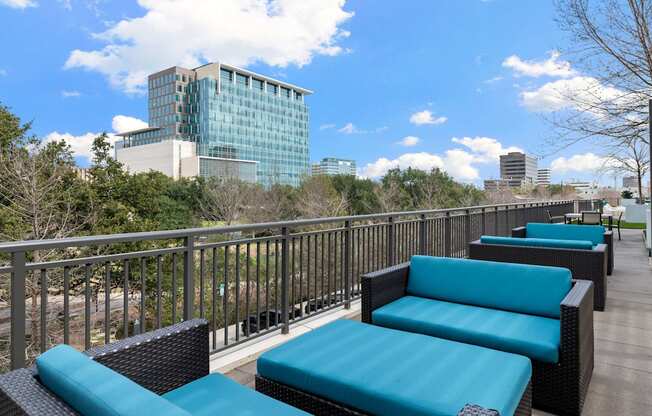 an outdoor deck with blue couches and chairs and a city in the background