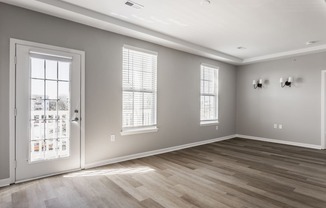 an empty living room with a door and windows