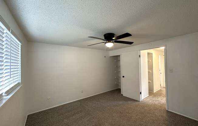 an empty bedroom with a ceiling fan