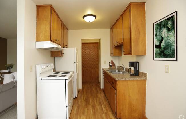 A kitchen with white appliances and wooden cabinets.