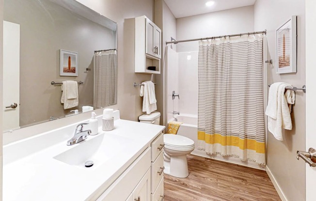 a bathroom with white cabinets and a yellow and white shower curtain