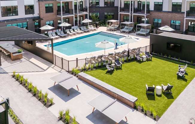 A large outdoor swimming pool surrounded by lounge chairs and umbrellas.