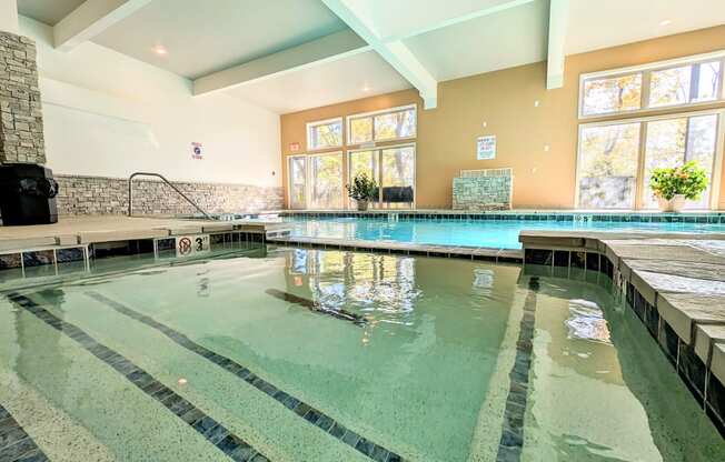 the indoor pool is heated and has large windows and a water feature
