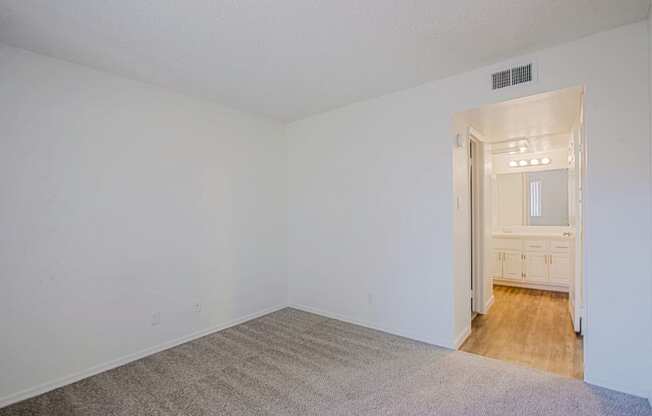 the living room of an empty apartment with white walls and wood flooring