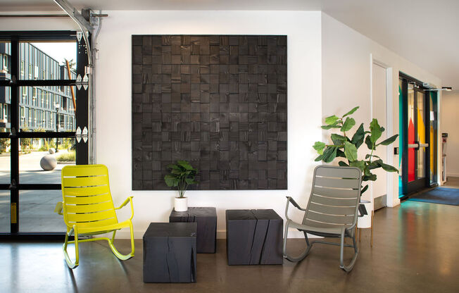 a black brick wall in the middle of a room with two yellow chairs in front of it