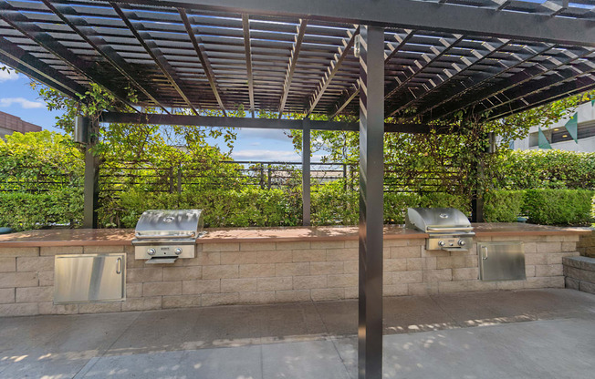 A patio with a grill and a pergola.