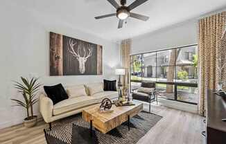 A living room with a white couch, a wooden coffee table, and a deer head picture on the wall. at Lazo Apartment Homes, Chandler Arizona