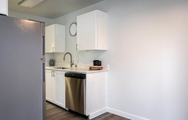 a kitchen with white cabinets and a stainless steel dishwasher