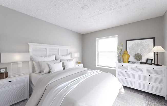 a white bedroom with a large bed and white dressers