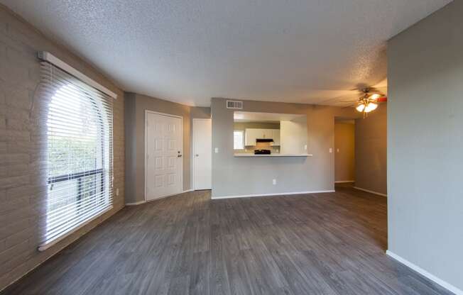 an empty living room with a large window and wood flooring