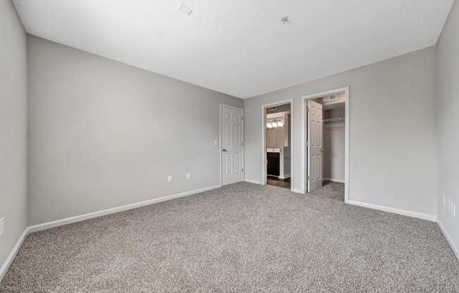 A spacious room with carpeted floor and two open doors.
