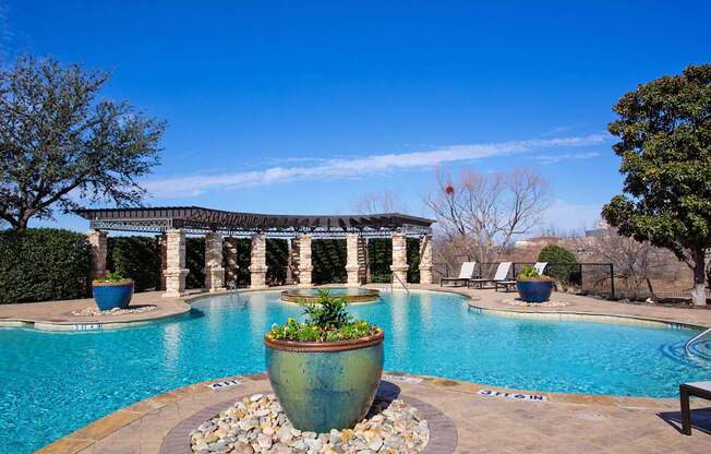 A large outdoor pool with a stone planter in the middle.
