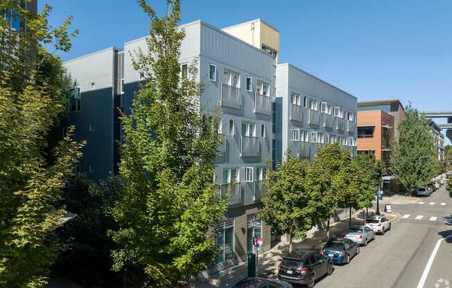A street view of a city with cars parked on the side of the road and buildings in the background.