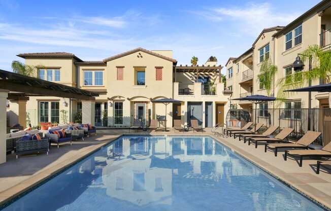 Apartments For Rent In Riverside, CA - Lincoln Village - Resort-Style Swimming Pool Outside With Sundeck, Lounge Chairs And Umbrellas
