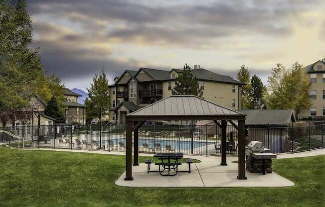 A covered picnic area with a pool in the background.
