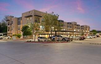 A parking lot in front of a building with cars parked.