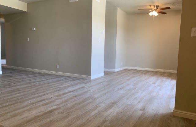 an empty living room with wood floors and a ceiling fan