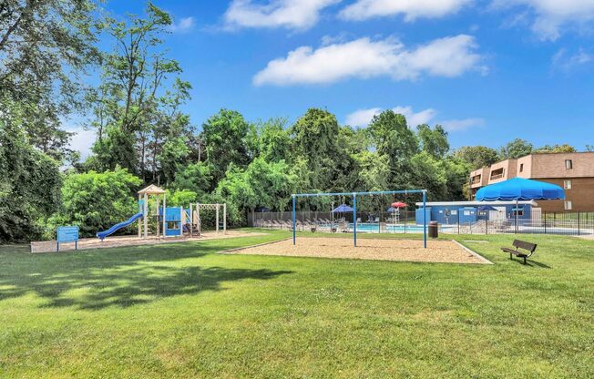 a grassy area with a playground and a building in the background