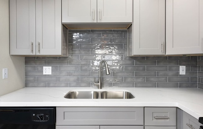 A kitchen with a black dishwasher and a stainless steel sink.