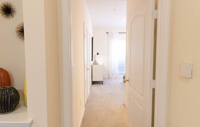 A hallway with a white door and a white wall.