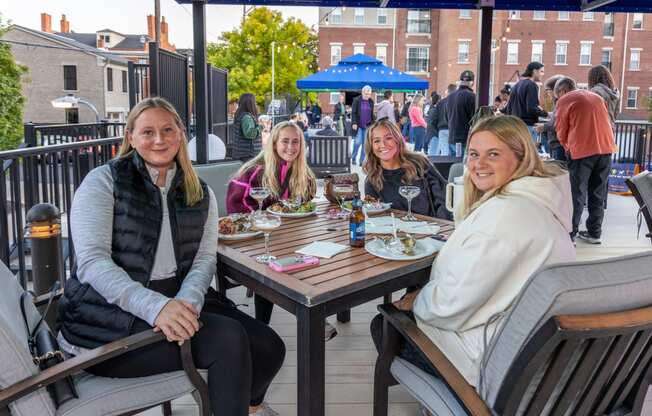 a group of women sitting at a patio table eating food