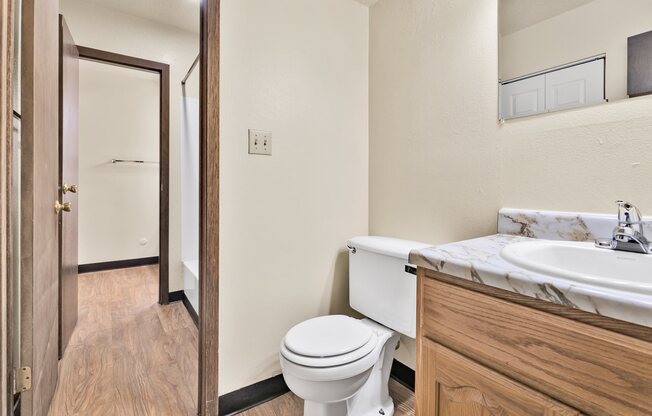 A white toilet sits in a bathroom next to a sink.