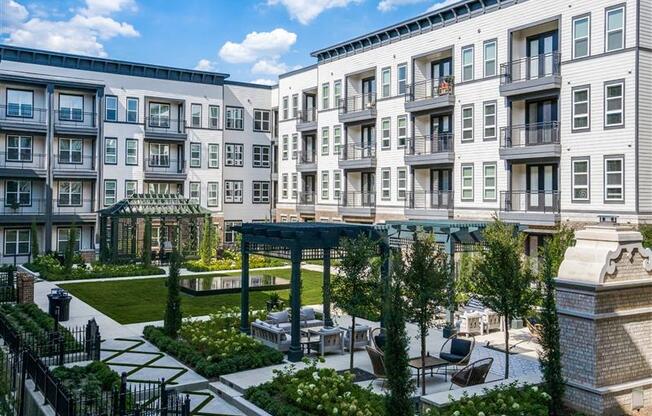 A sunny day at a residential complex with a well-maintained garden and outdoor seating area.